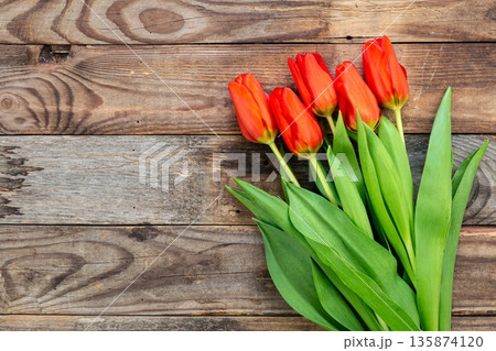 Bouquet of red tulips on a wooden background, top view. Bouquet of red tulips on a wooden background, top view. 135874120