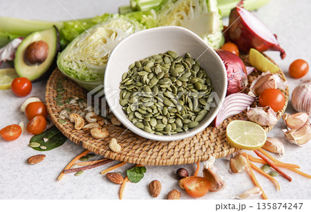 Close-up, a bowl of pumpkin seeds and other healthy foods on the kitchen table. 135874247