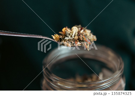 Close-up of a teaspoon and a jar of herbal tea. 135874325