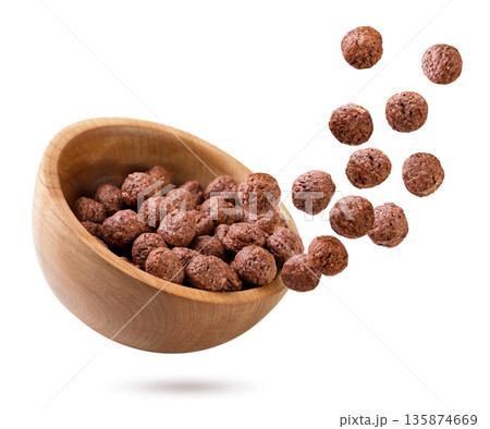 Chocolate corn balls fly out of a wooden plate on a white. Isolated Chocolate corn balls fly out of a wooden plate on a white. Isolated 135874669