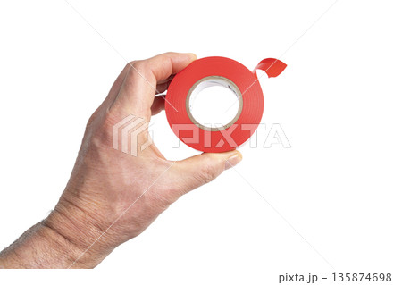 a roll of red electrical tape in the hand a roll of red electrical tape in the hand 135874698