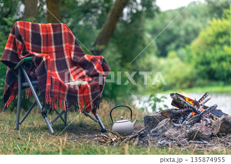 Small kettle is heated on a bonfire, outdoor recreation concept. Small kettle is heated on a bonfire, outdoor recreation concept. 135874955