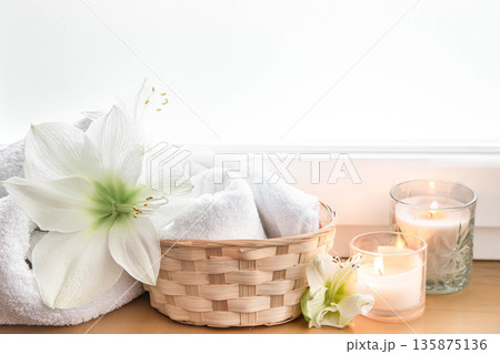 Spa composition with lily flowers and towels in a basket. 135875136