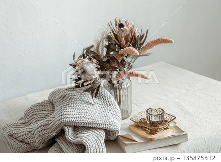 Cozy composition with a bouquet of dried flowers and home decor details. 135875312