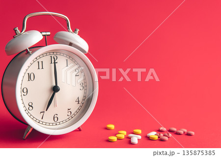 Time for health check concept. White alarm clock with pills. 135875385