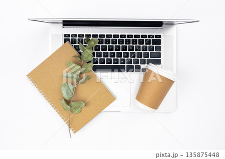 White background with laptop, notepad and disposable glass, top view. 135875448