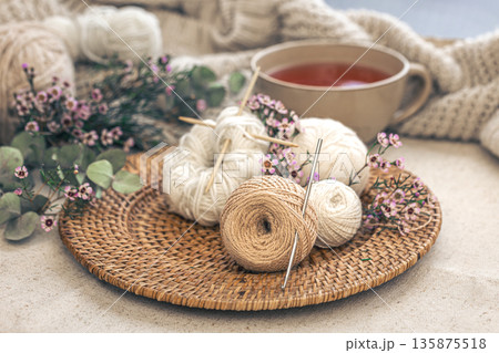 Cozy composition with knitting threads, a cup of tea and flowers. 135875518