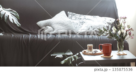 Cozy home interior living room with a black sofa and a vase of flowers 135875536