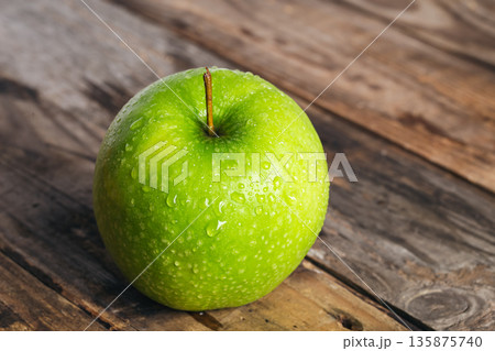 Green apple with water drops on a wooden background close-up. 135875740