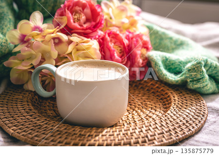 Home composition with a cup of coffee, flowers and a knitted element. Home composition with a cup of coffee, flowers and a knitted element. 135875779