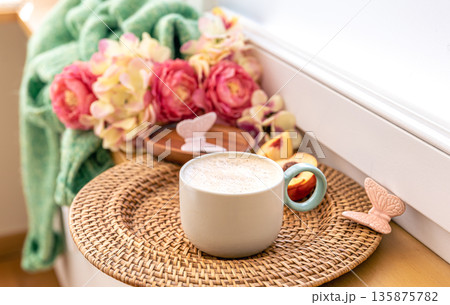 Home composition with a cup of coffee, flowers and a knitted element. Home composition with a cup of coffee, flowers and a knitted element. 135875782