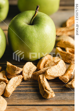 Homemade dried organic apple and and raw green apples on a wood background. 135875799
