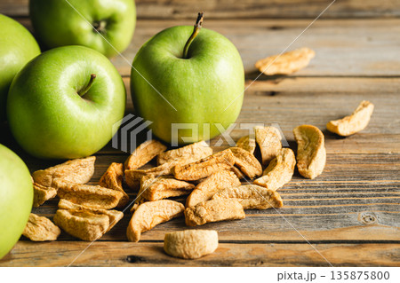 Homemade dried organic apple and and raw green apples on a wood background. Homemade dried organic apple and and raw green apples on a wood background. 135875800