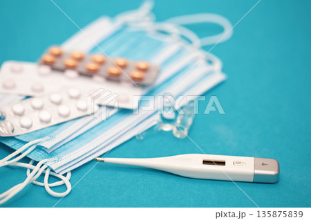 Medical background with thermometer, pills and masks close-up. Medical background with thermometer, pills and masks close-up. 135875839