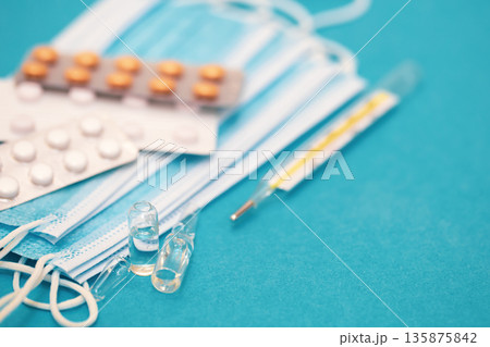 Medical background with thermometer, pills and masks close-up. Medical background with thermometer, pills and masks close-up. 135875842