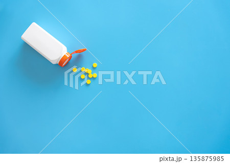 Pills are poured out of a jar on a blue background., flat lay. Pills are poured out of a jar on a blue background., flat lay. 135875985