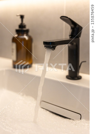 Black faucet flow. Foamy water. Warm backlight Black faucet flow. Foamy water. Warm backlight 135876459