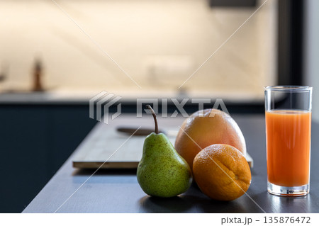 Bright juice glass beside orange, pear and grapefruit. Vitamin boost. 135876472