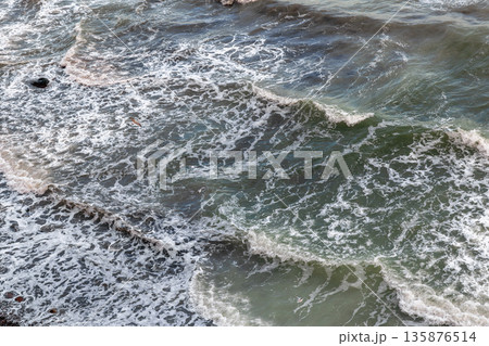 Foamy waves on greenish sea, rhythm and texture. Sea foam closeup. Foamy waves on greenish sea, rhythm and texture. Sea foam closeup. 135876514