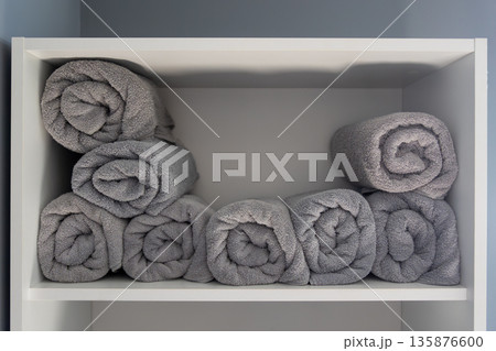 Neatly rolled grey towels on modern shelf. Rolled towels. Neatly rolled grey towels on modern shelf. Rolled towels. 135876600
