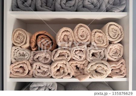 Rolled spa towels on shelf in soft neutrals. Spa towels. 135876629