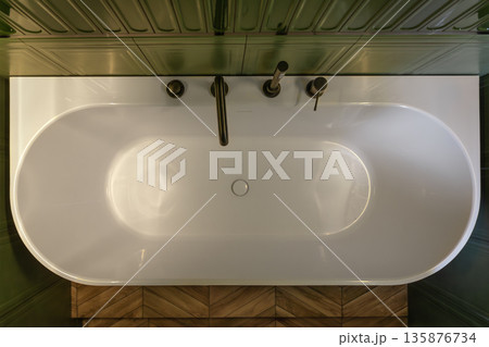 White bathtub top view amid green tiles. Top view. 135876734