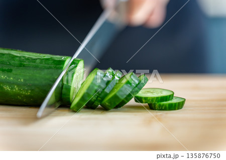 Woman cutting cucumber with knife macro view. Thick slices. 135876750