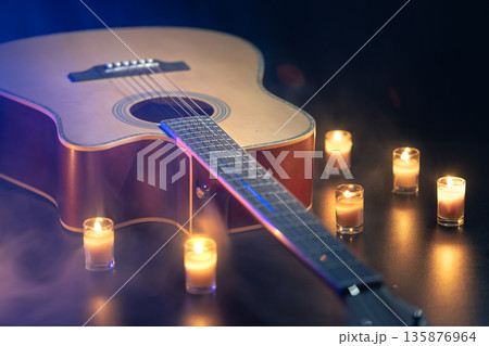 Acoustic guitar on a black background with candles. 135876964