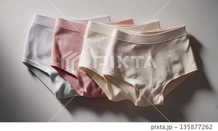 Collection of four pairs of comfortable cotton underwear in pastel colors, neatly arranged on a soft surface, showcasing modern design and everyday essentials for women 135877262