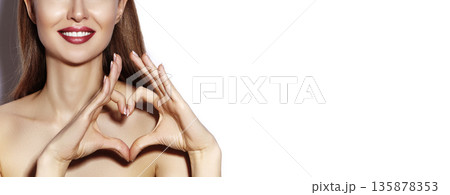 Smiling beautiful woman forming heart shape with hands. Valentine Day concept, happy girl, bright makeup for date, red lipstick. Beauty mockup for cosmetic branding, romantic mood, feminine style. 135878353
