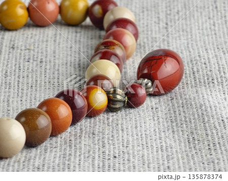 Prayer beads made of mukaite jasper against a burlap background. The 33-bead prayer beads are traditionally used for meditation by people of various faiths. Prayer beads made of mukaite jasper against a burlap background. The 33-bead prayer beads are traditionally used for meditation by people of various faiths. 135878374