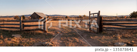 A classic farm gate made of wooden panels stands beside a lush green pasture. The cloudy sky adds a tranquil atmosphere to this rural landscape, making it peaceful and inviting, banner 135878641