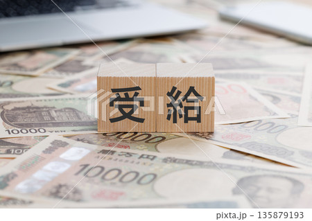 お金の上に受給と書かれたブロック 135879193