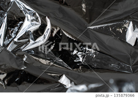 Deep dark crumpled metallic foil texture with dramatic shadows 135879366