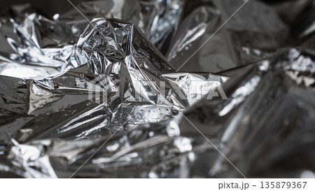Chaotic dark metallic foil texture with sharp abstract folds 135879367