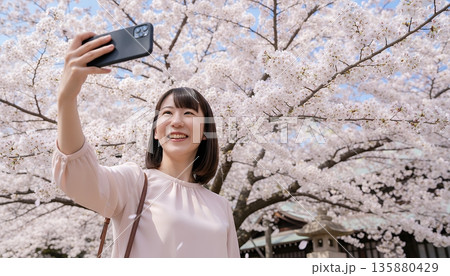 満開の桜の前で自撮りをする若い女性 満開の桜の前で自撮りをする若い女性 135880429
