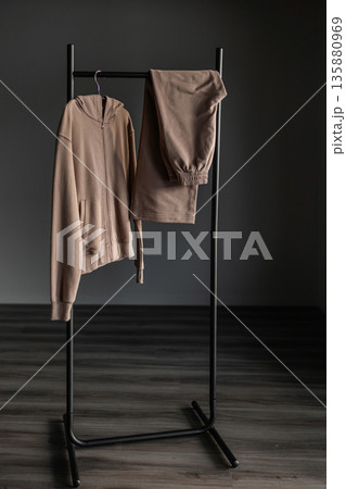 Hoodie and pants displayed on a black clothing rack in a simple indoor setting 135880969