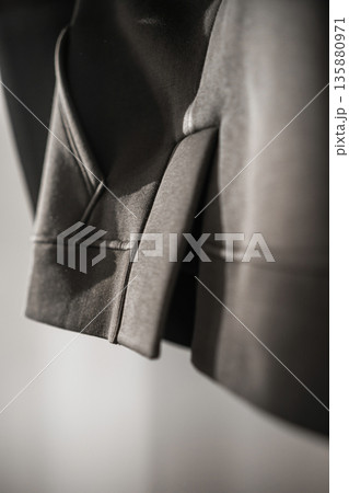 Close view of a gray hoodie hanging on a wall in a simple indoor space during bright daylight 135880971