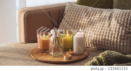 Candles and Reed Diffuser on Wooden Tray. Cozy Home Decor lifestyle with Cushions Candles and Reed Diffuser on Wooden Tray. Cozy Home Decor lifestyle with Cushions 135881153