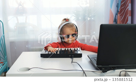 Little girl in headphones and sunglasses crafting music on a midi keyboard at home, creative hobby 135881512