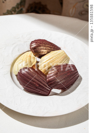 Assorted chocolate madeleine cakes on white plate Assorted chocolate madeleine cakes on white plate 135881598