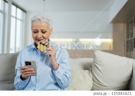 Senior woman shopping online with smartphone paying with credit card at home Old lady buying on Internet enter credit card details Online shopping delivery service. Older generation modern tech usage Senior woman shopping online with smartphone paying with credit card at home Old lady buying on Internet enter credit card details Online shopping delivery service. Older generation modern tech usage 135881821
