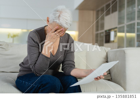 Sad tired ill sick lonely disappointed older senior woman reading bad news at home alone. Unhappy mature grandmother experiencing grief relative death. Stressed elder lady with paper document bill Sad tired ill sick lonely disappointed older senior woman reading bad news at home alone. Unhappy mature grandmother experiencing grief relative death. Stressed elder lady with paper document bill 135881851