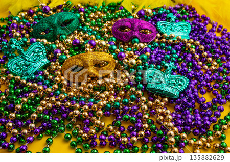 Mardi Gras beads in glittering yellow, green, purple, and gold. Sparkling festive background for Mardi Gras in traditional colors. Mardi Gras beads in glittering yellow, green, purple, and gold. Sparkling festive background for Mardi Gras in traditional colors. 135882629