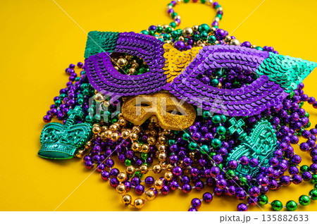 Mardi Gras beads in glittering yellow, green, purple, and gold. Sparkling festive background for Mardi Gras in traditional colors. Mardi Gras beads in glittering yellow, green, purple, and gold. Sparkling festive background for Mardi Gras in traditional colors. 135882633