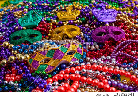 Mardi Gras beads in glittering yellow, green, purple, and gold. Sparkling festive background for Mardi Gras in traditional colors. 135882641