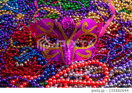 Mardi Gras beads in glittering yellow, green, purple, and gold. Sparkling festive background for Mardi Gras in traditional colors. 135882644
