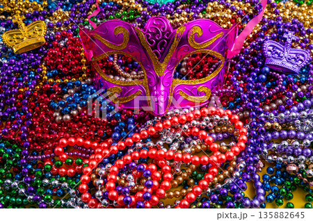 Mardi Gras beads in glittering yellow, green, purple, and gold. Sparkling festive background for Mardi Gras in traditional colors. 135882645