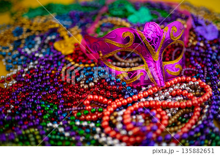 Mardi Gras beads in glittering yellow, green, purple, and gold. Sparkling festive background for Mardi Gras in traditional colors. 135882651