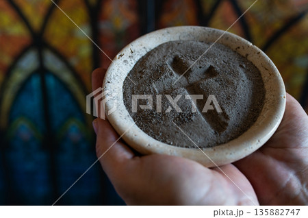 Hands with gray ash cross in church on stained glass window. background. Ash Wednesday Hands with gray ash cross in church on stained glass window. background. Ash Wednesday 135882747